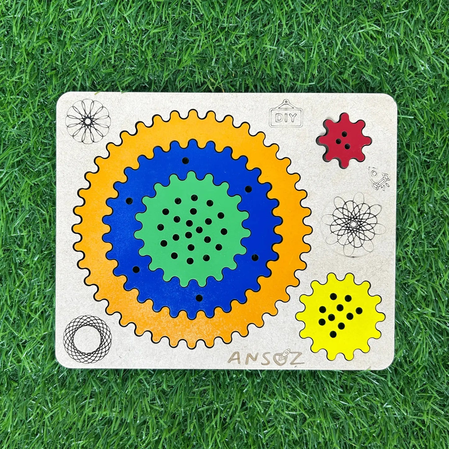 A wooden Ansoz gear puzzle toy for children, featuring concentric colored gears (yellow, blue, green) and smaller red and yellow gears on a light wood base, placed on a green grass background.