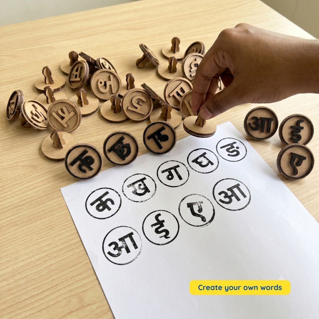 A child-friendly Hindi learning activity showing wooden Hindi Swar and Vyanjan stamps being used to print letters on paper. The hands-on activity helps children recognize Hindi alphabet letters, improve fine motor skills, and build early literacy skills.