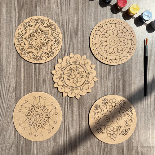 Wooden mandala painting kit with five engraved MDF coasters, paint bottles, and a paintbrush for DIY art and craft activities.