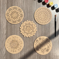 Wooden mandala painting kit with five engraved MDF coasters, paint bottles, and a paintbrush for DIY art and craft activities.