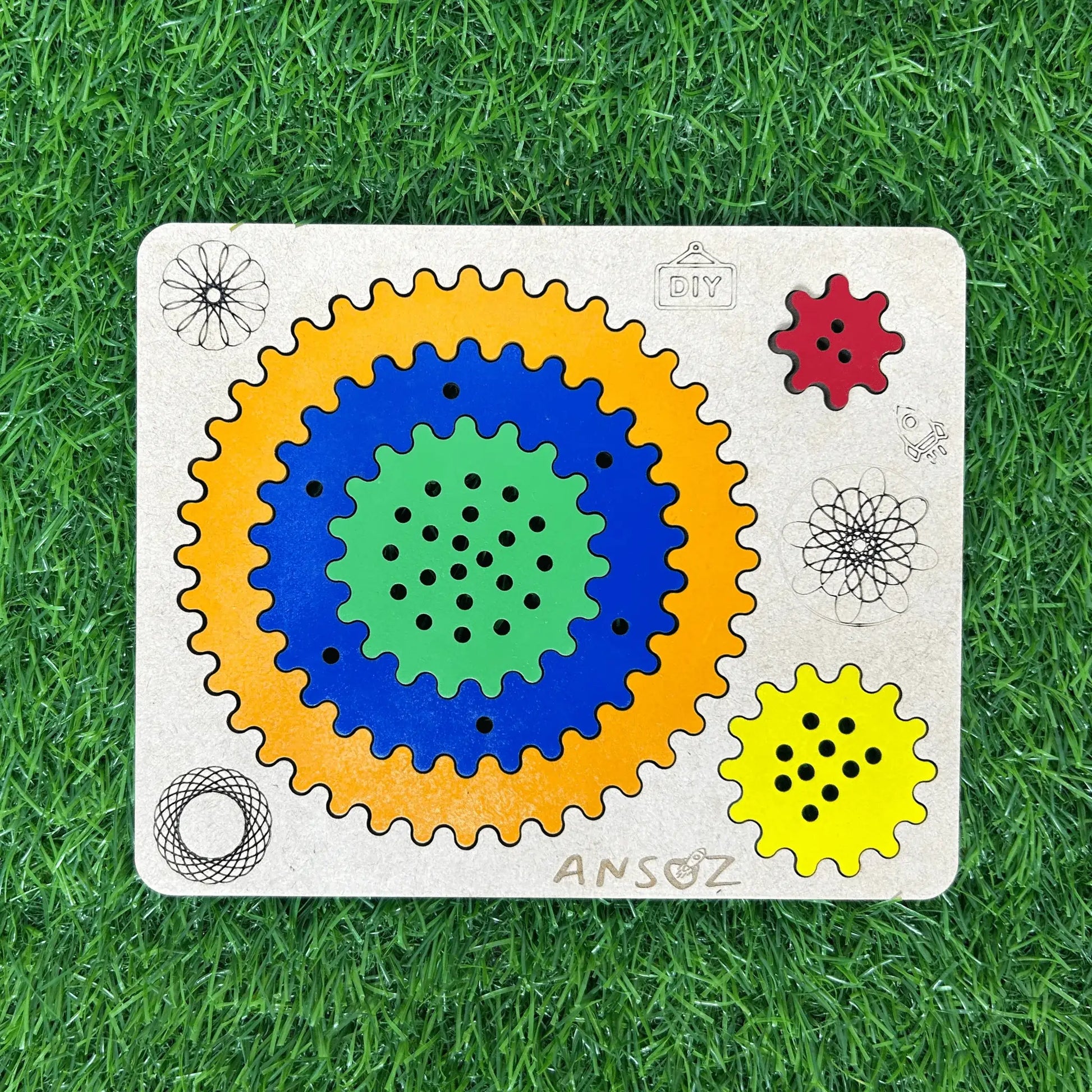 A wooden Ansoz gear puzzle toy for children, featuring concentric colored gears (yellow, blue, green) and smaller red and yellow gears on a light wood base, placed on a green grass background.