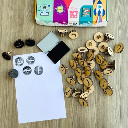 Urdu alphabet stamps kit with stamps, ink pad, and papers for children to learn Urdu letters with a stamping game.

