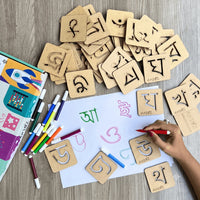 Hand tracing Assamese alphabet using a reusable wooden stencil on paper with sketch pens, helping children develop handwriting, fine motor skills, and letter recognition.