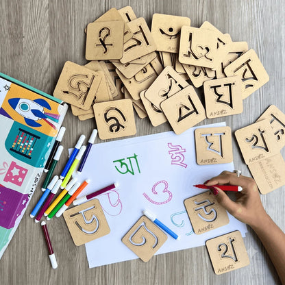 Hand tracing Assamese alphabet using a reusable wooden stencil on paper with sketch pens, helping children develop handwriting, fine motor skills, and letter recognition.