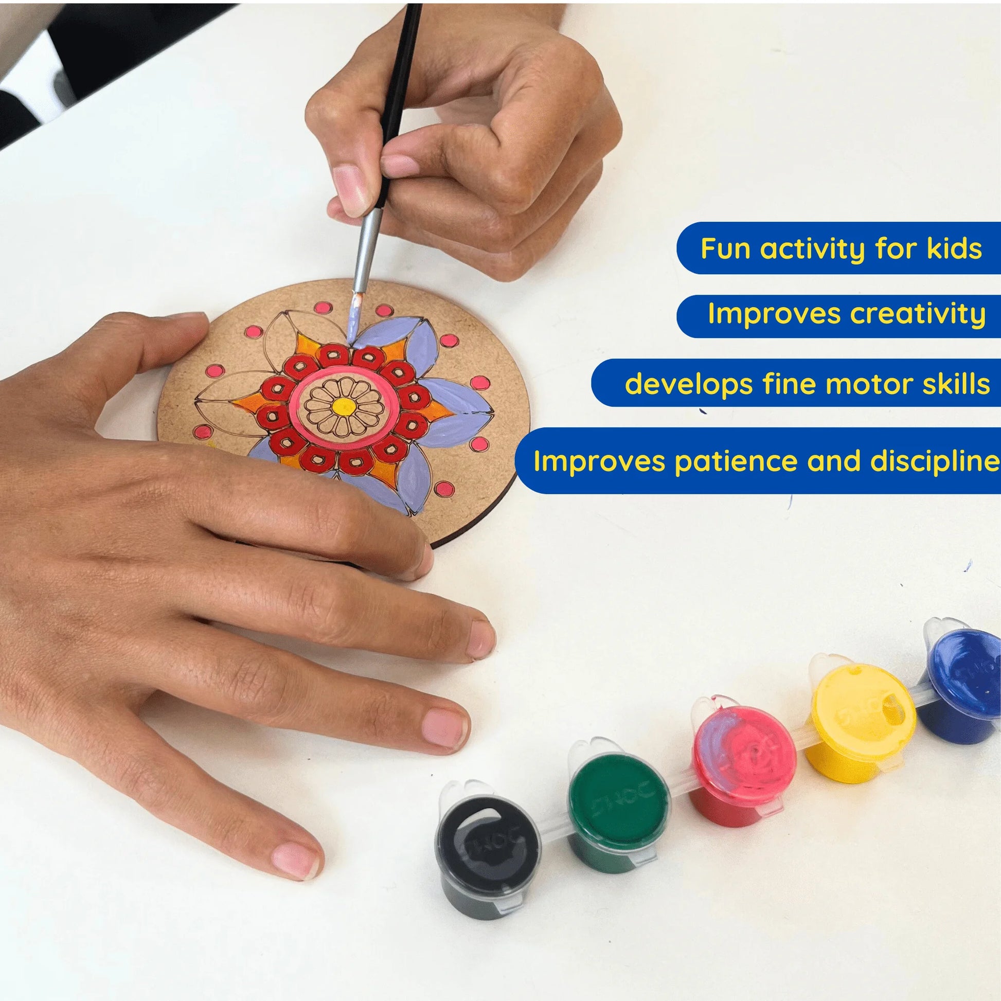 A person's hands are shown painting a circular wooden plaque with a colorful mandala design, with four small paint pots lined up on a white table. Blue text overlays on the right list benefits like 'Fun activity for kids' and 'Improves creativity'.