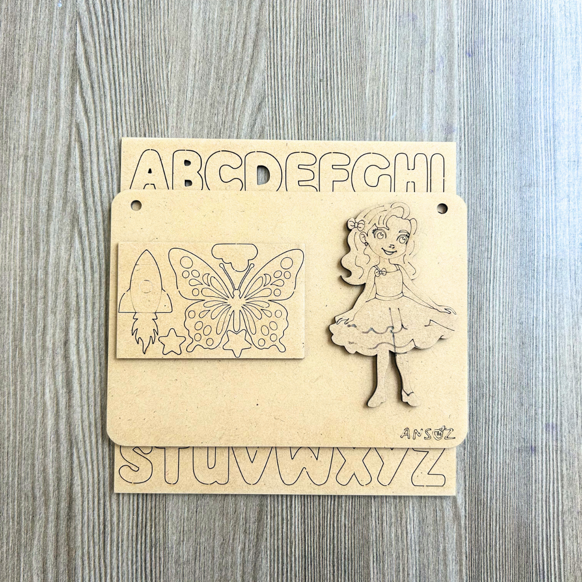 Kids name plate craft kit consisting of wooden board, alphabet stickers, and decorative items for making name plates out of wood.
