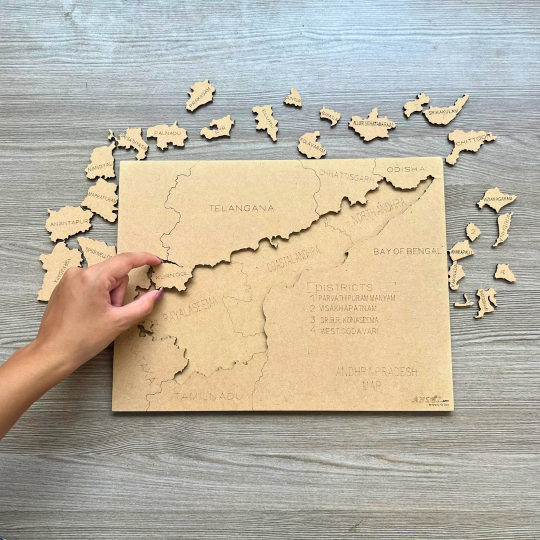 Hand placing district pieces on a wooden Andhra Pradesh map puzzle.