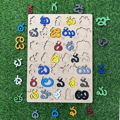 A wooden puzzle board featuring cutout shapes and colorful Telugu letters arranged around it on a green grass-like surface.