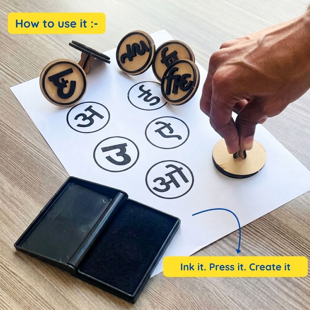 A hand presses a wooden Hindi alphabet stamp onto paper after inking it on an ink pad. The image demonstrates the simple process: ink the stamp, press it onto paper, and create Hindi letters and words for fun educational practice.