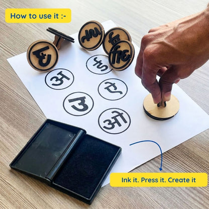 A hand presses a wooden Hindi alphabet stamp onto paper after inking it on an ink pad. The image demonstrates the simple process: ink the stamp, press it onto paper, and create Hindi letters and words for fun educational practice.