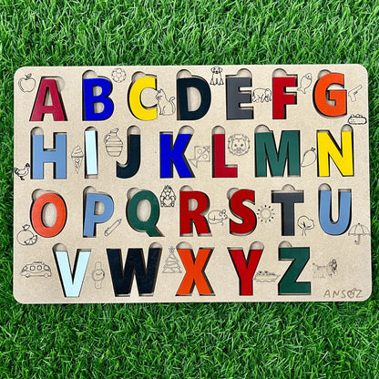 A wooden alphabet puzzle board for children, featuring colorful cutout letters with animal and object illustrations, displayed on a green grass background.