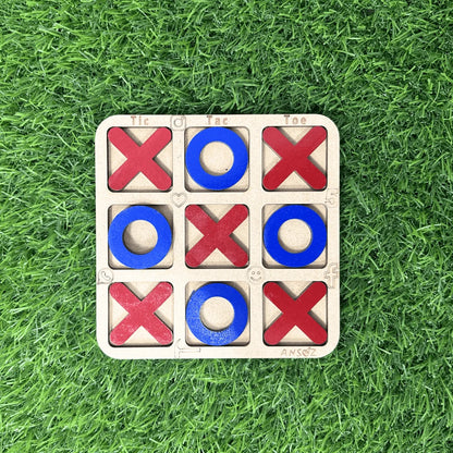 A wooden 3-in-1 tic-tac-toe game board with red Xs and blue Os, placed on a green grass background.